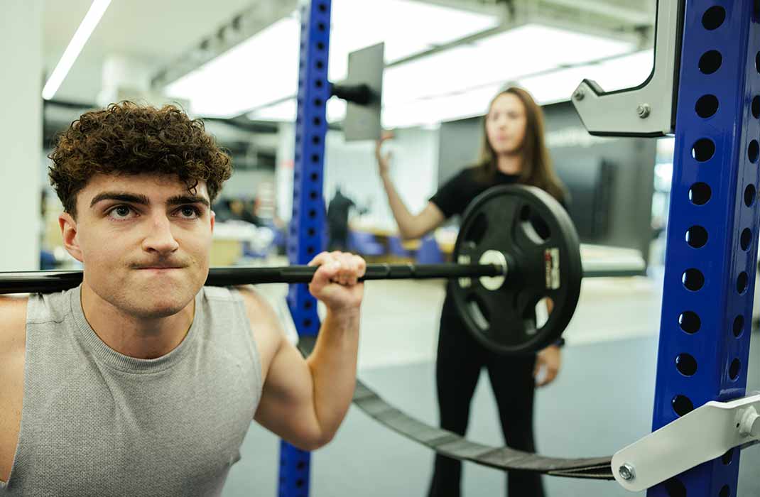 male athlete squatting with barbell on his shoulders