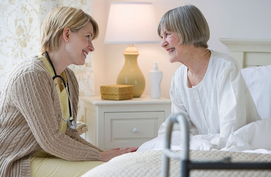 Female home care provider at the bedside of older female patient